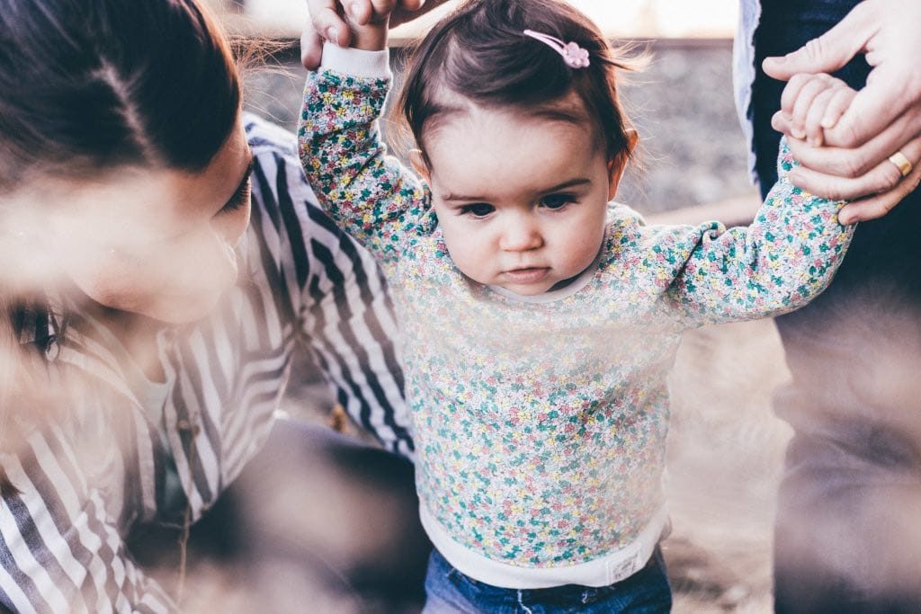 little girl with parents learning to walk